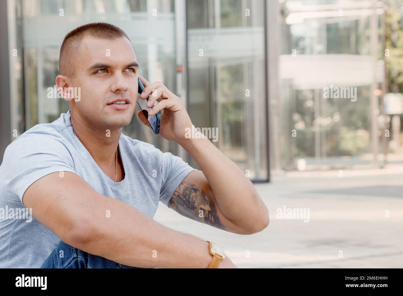 Young man talking on a cell phone. A guy with a tattoo on his arm. Handsome guy in the city. Stock Photo