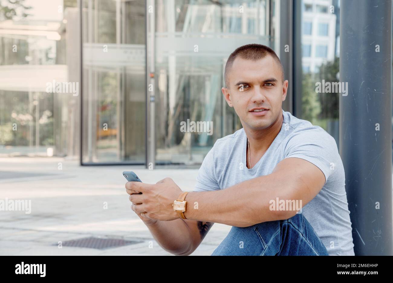 Young man talking on a cell phone. A guy with a tattoo on his arm. Handsome guy in the city. Stock Photo