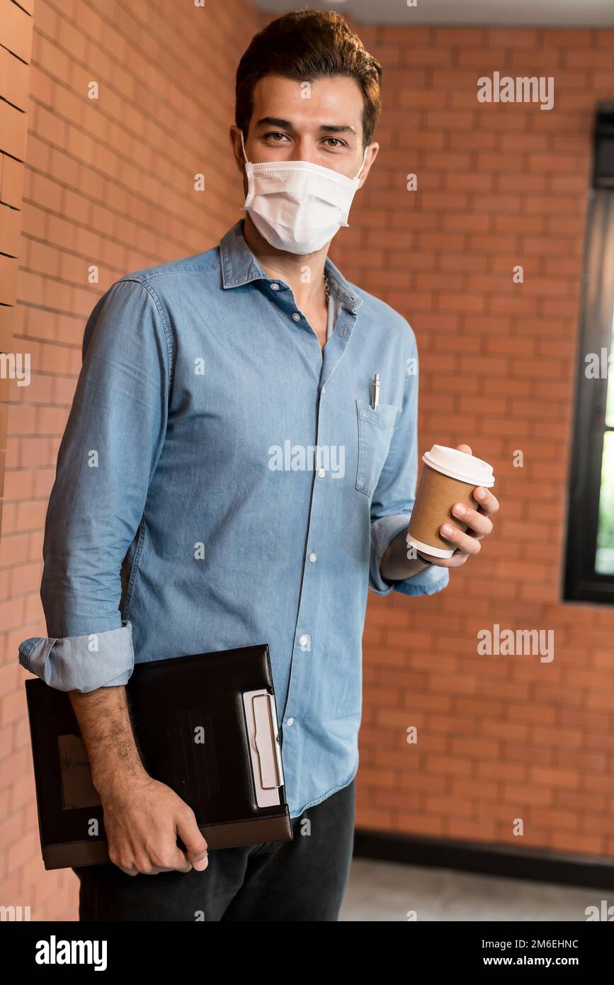 Portrait of middle east businessman with face mask hold coffee cup Stock Photo