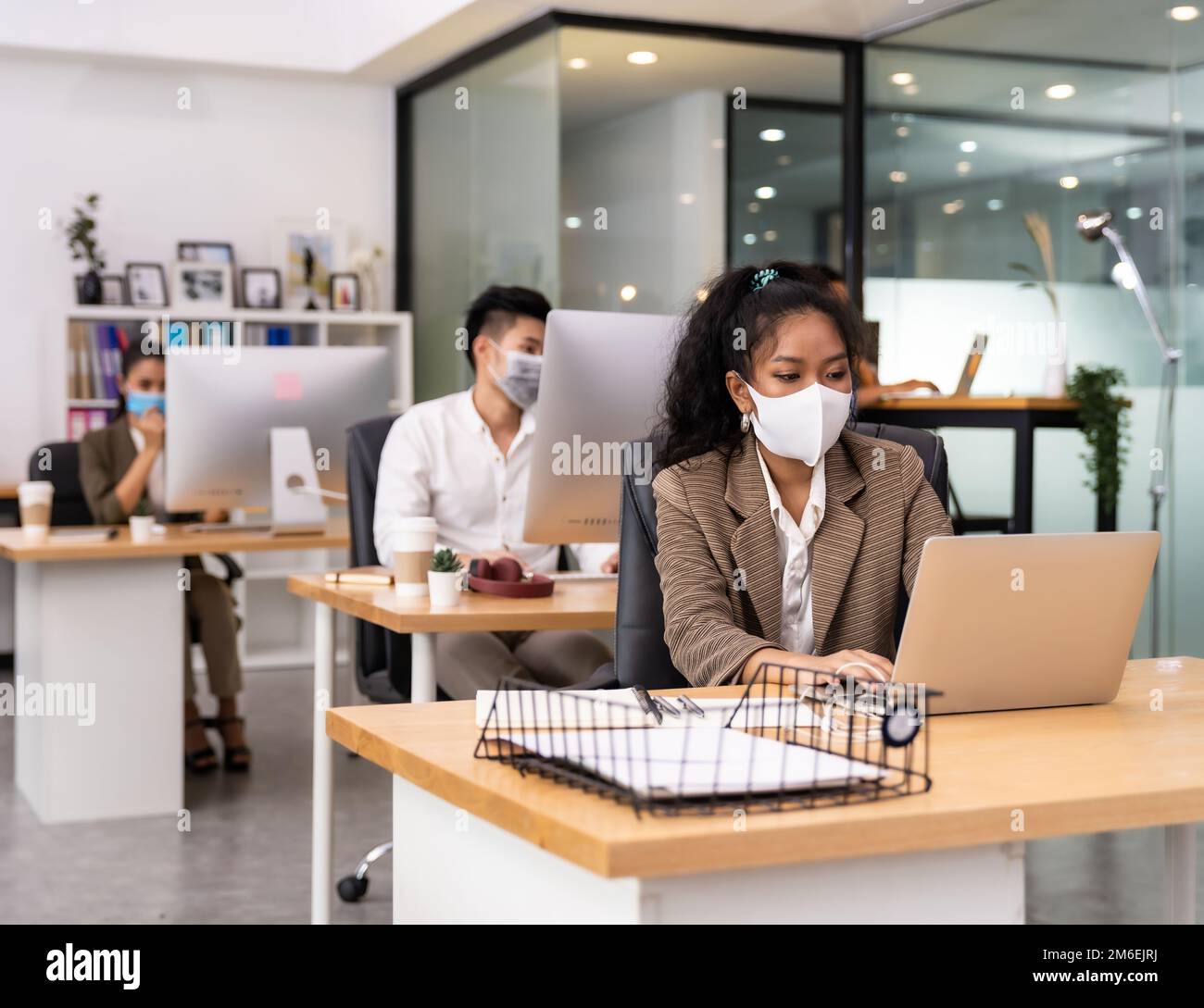 African office worker with asian team in new normal social distance office Stock Photo