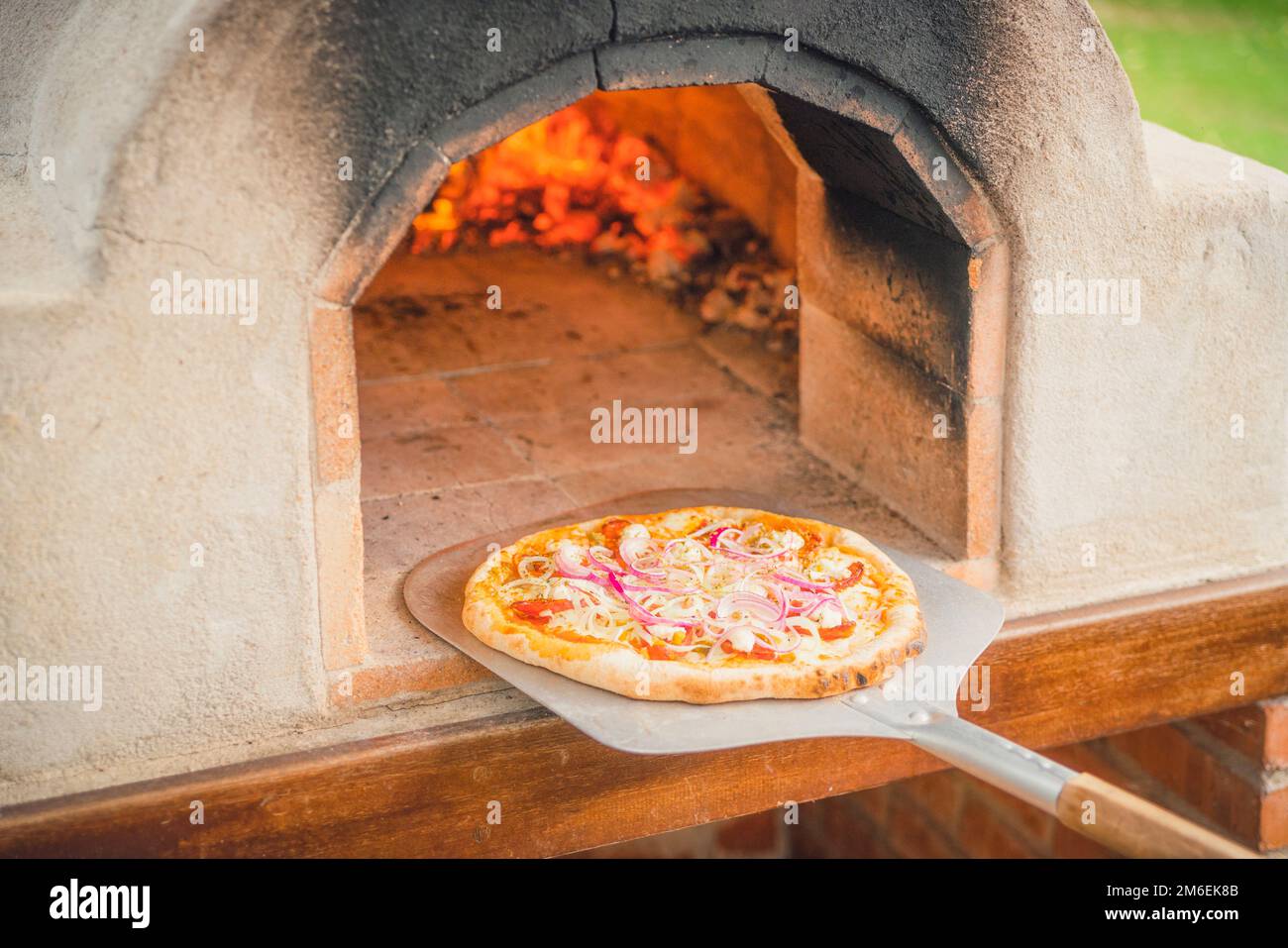 Delicious pizza from a hot outdoor stone oven with fire taken out with