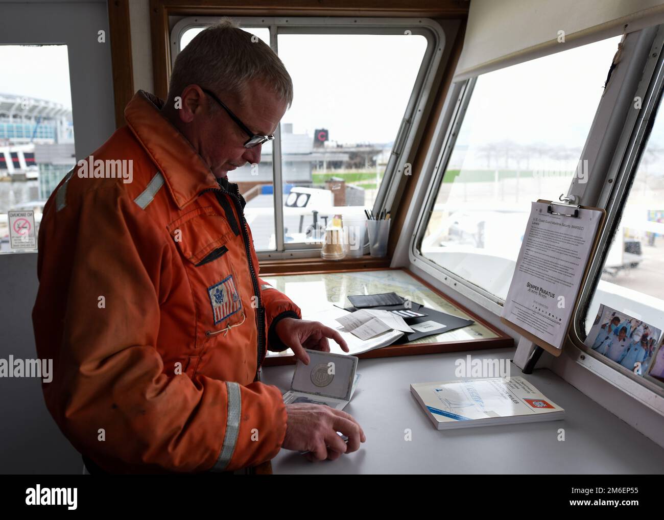 U.S. Coast Guard Chief Warrant Officer Robie Moorhouse, a marine inspector at Marine Safety Unit (MSU) Cleveland, inspects the captain’s license during a vessel inspection April 26, 2022, in Cleveland, Ohio. MSU Cleveland conducts vessel inspections to make sure vessels are in compliance safety, security, and environmental regulations. Stock Photo
