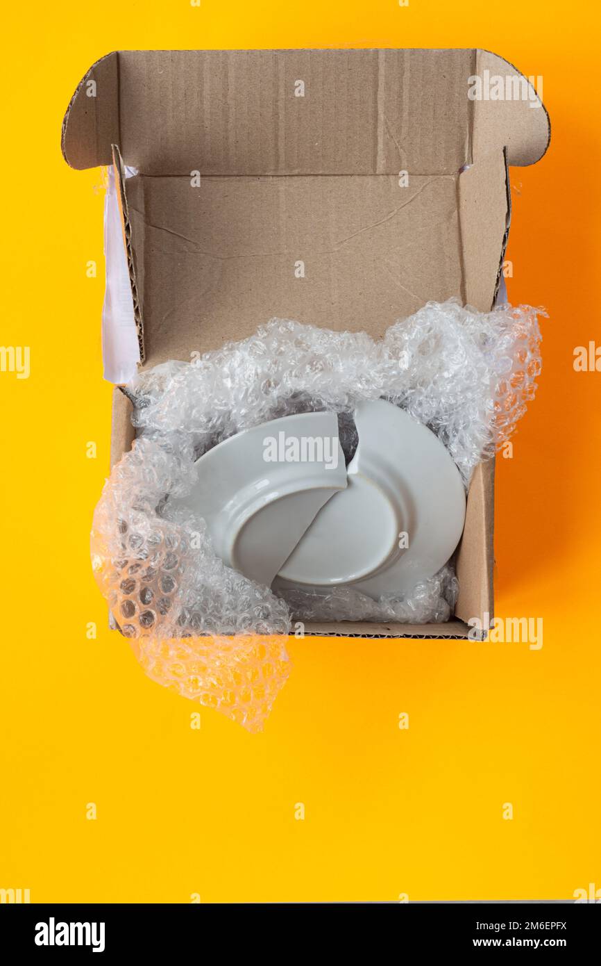 Upon opening, the parcel contained a broken plate, yellow background Stock Photo