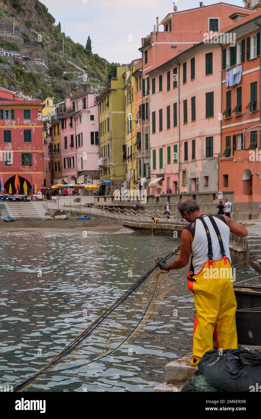 Fisherman With Fishing Nets - Beautiful Natural Harbor with Colorful Traditional Houses - Vernazza, Cinque Terre, Italy Stock Photo