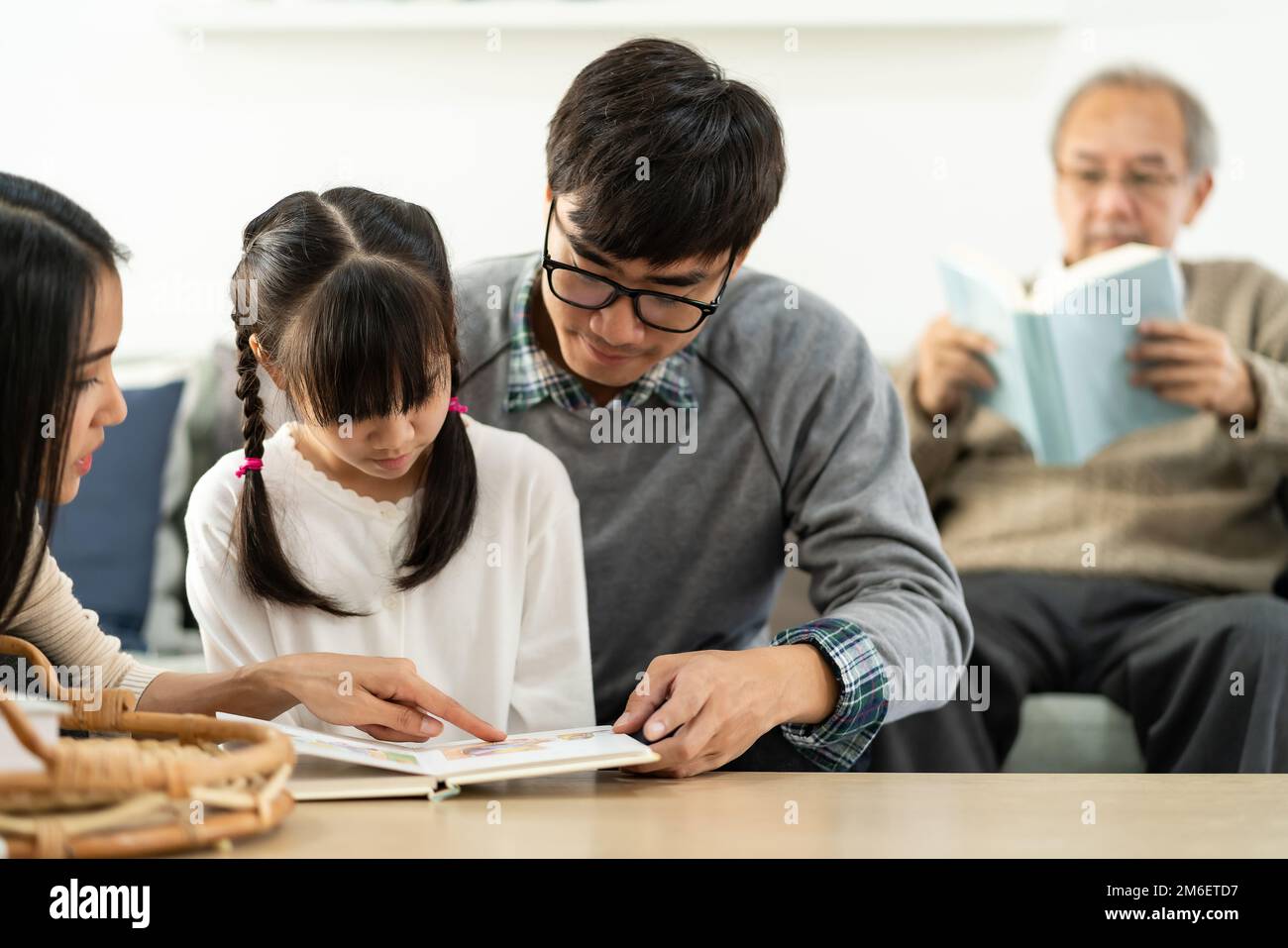Daughter reading story with multigenerational family Stock Photo - Alamy