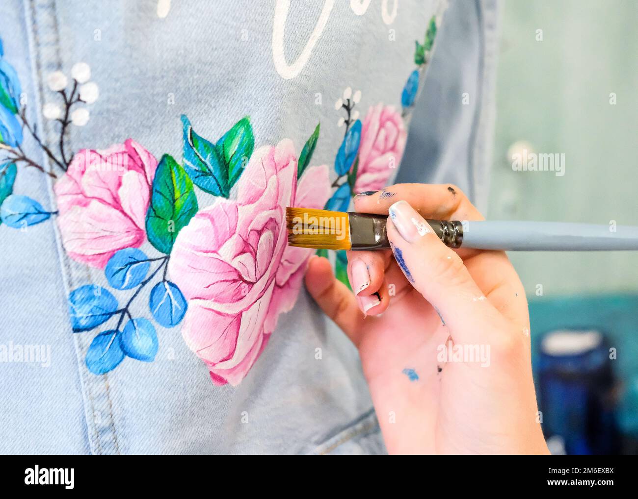 Painting flowers on a denim jacket. Details Stock Photo
