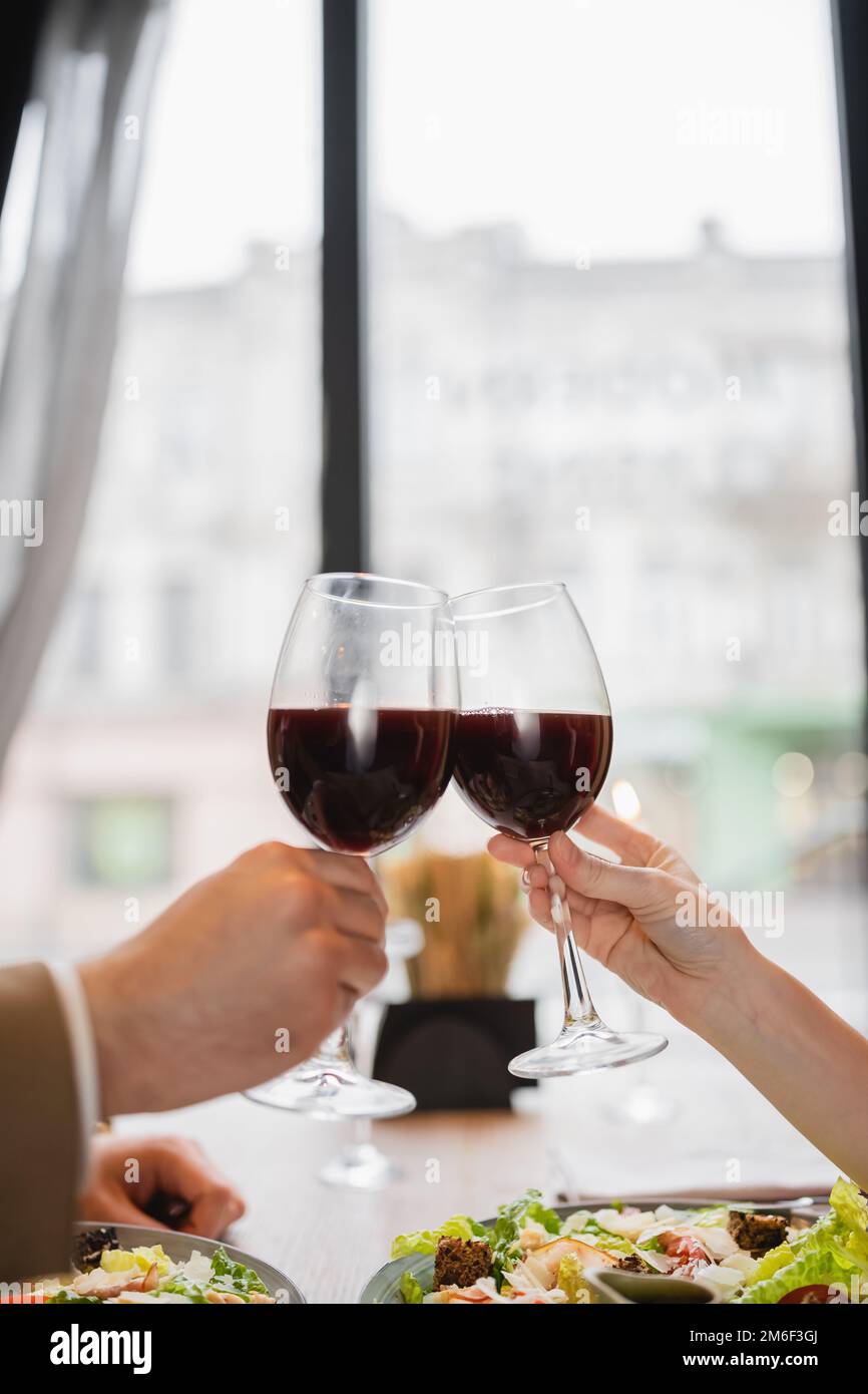 partial view of couple clinking glasses with red wine during celebration on  valentines day,stock image Stock Photo - Alamy
