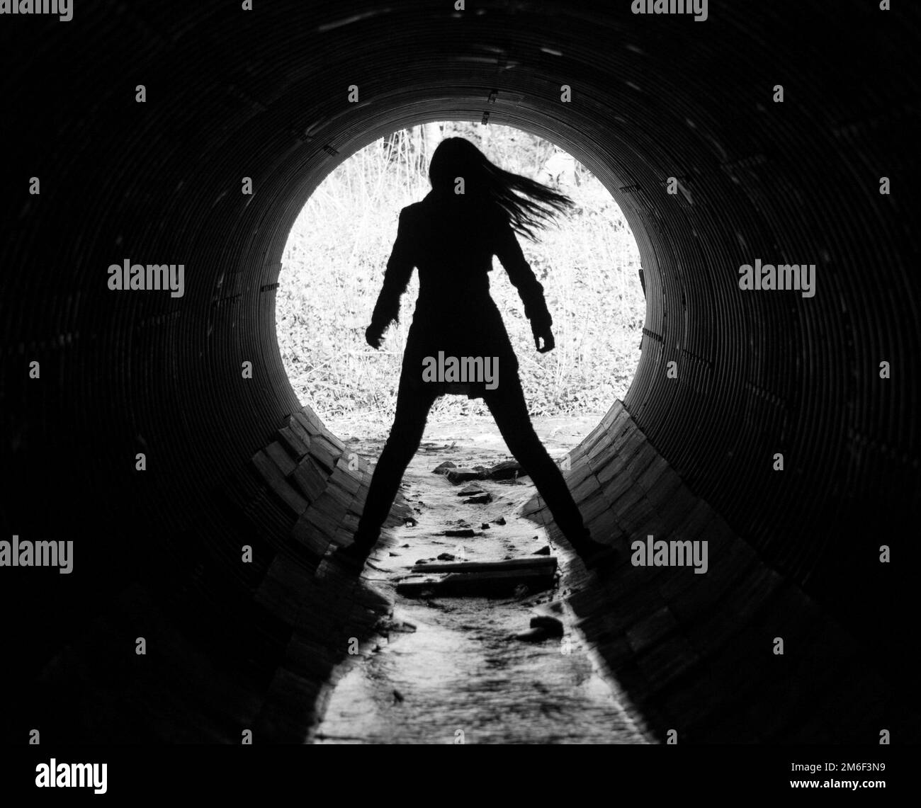 Silhouette of a young woman in the coc of the tunnel. A sewer tunnel under the road. Stock Photo