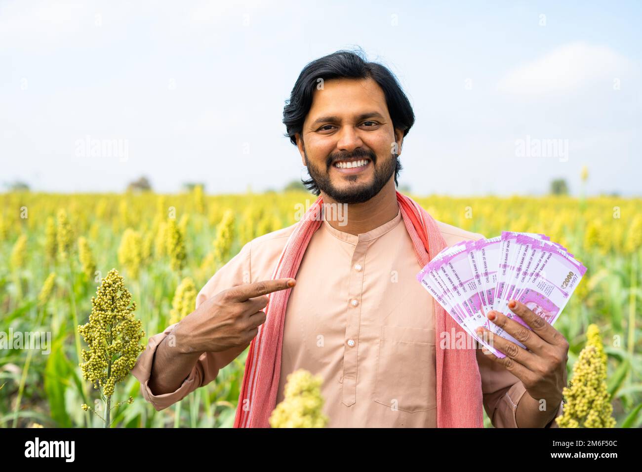 Happy smiling young farmer showing money or currency by pointing finger