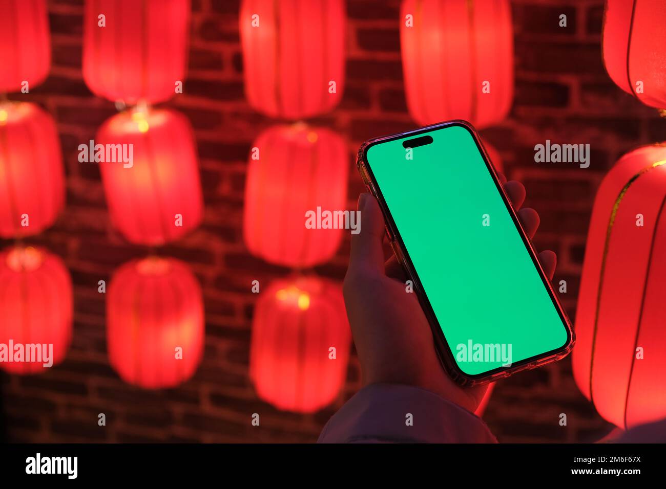 hand hold green screen phone with blur traditional Chinese red lanterns. Chinese new year concept Stock Photo