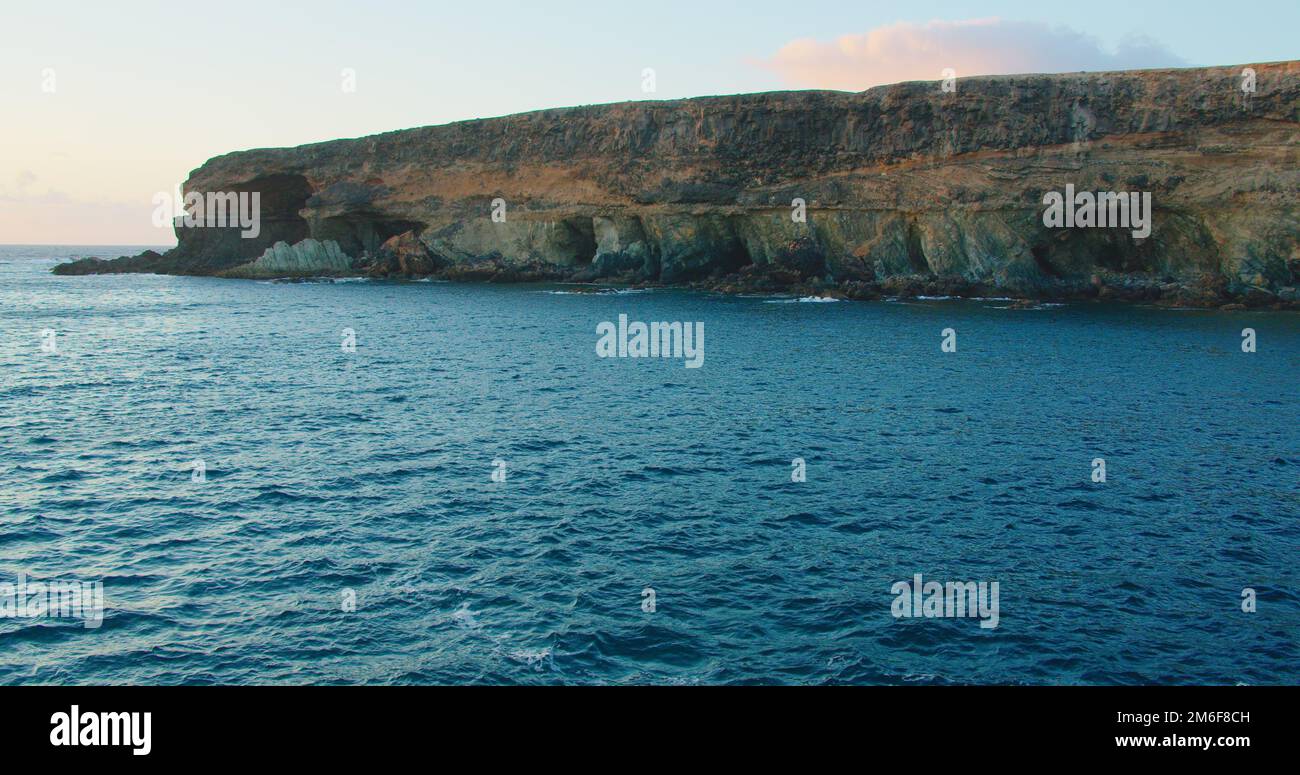 Azure calm ocean waves and rocky black volcanic caves cliffs of Ajuy in