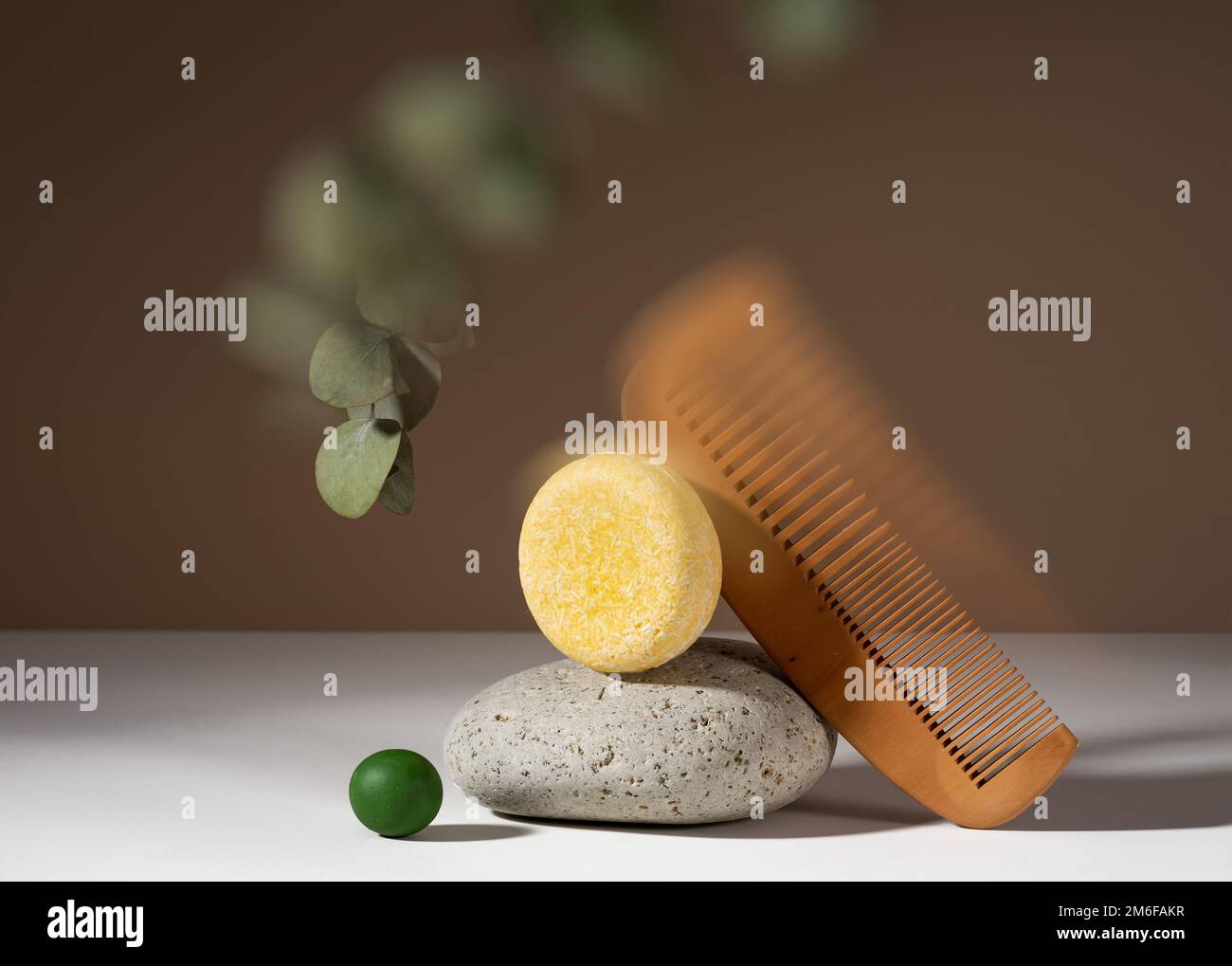 Modern still life composition of a solid shampoo bar with kaleidoscopic glitch effect. Shampoo bar and a wooden comb balancing on a brown background. Stock Photo