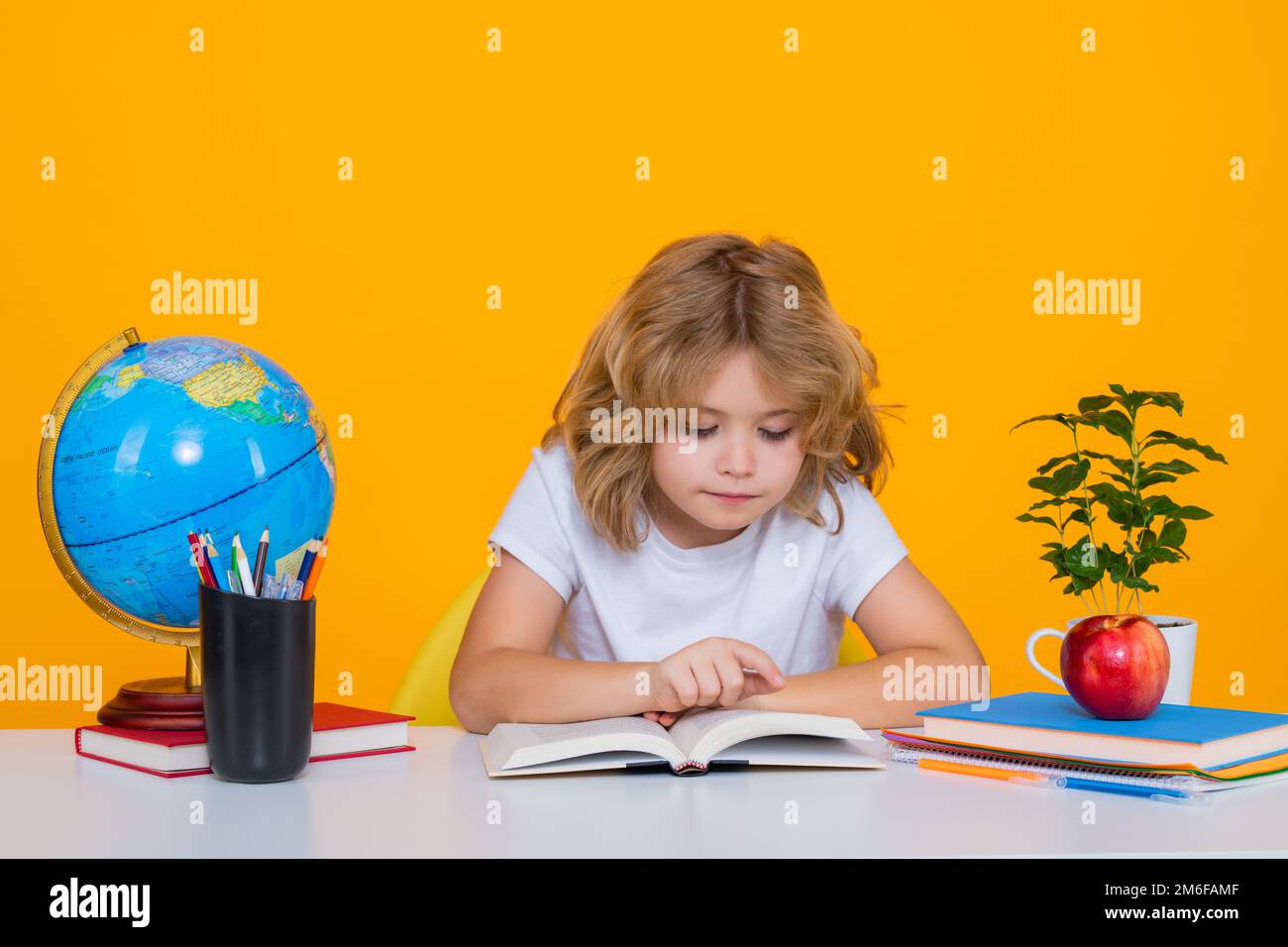 School kid reading book. Nerd pupil boy from elementary school with book isolated on yellow studio background. Smart genius intelligence kid ready to Stock Photo