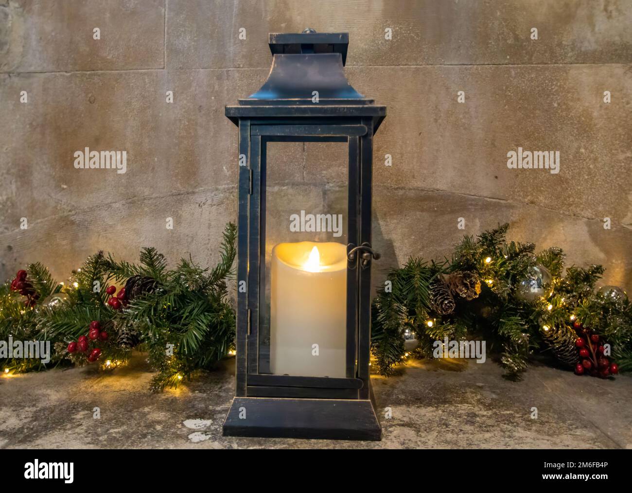An old storm lantern and candle in front of Christmas decorations in Winchester, Hampshire, UK Stock Photo