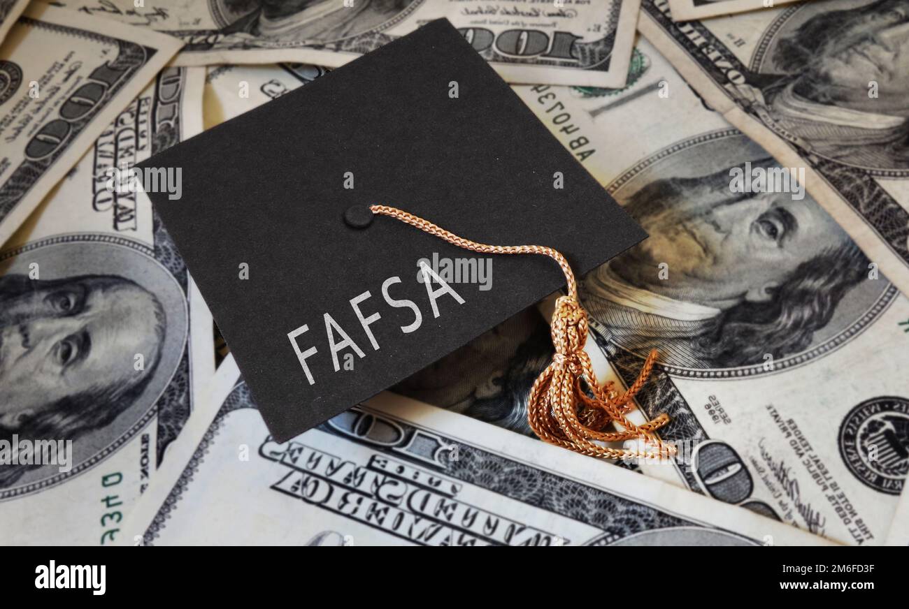 FAFSA (Free Application for Federal Student Aid) text on graduation cap and money - financial aid concept Stock Photo