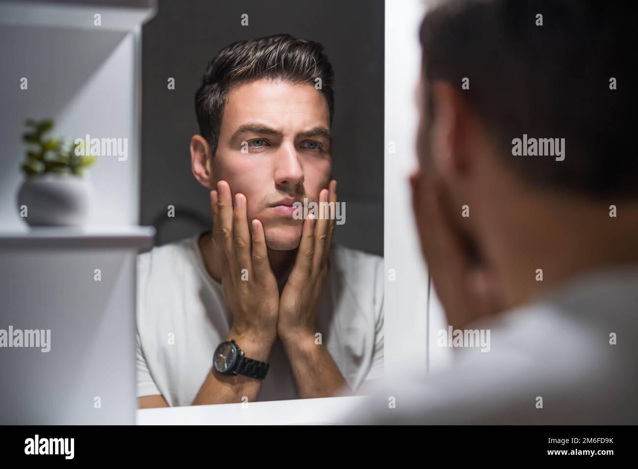 Tired man looking his eye bags and wrinkles while standing in front of
