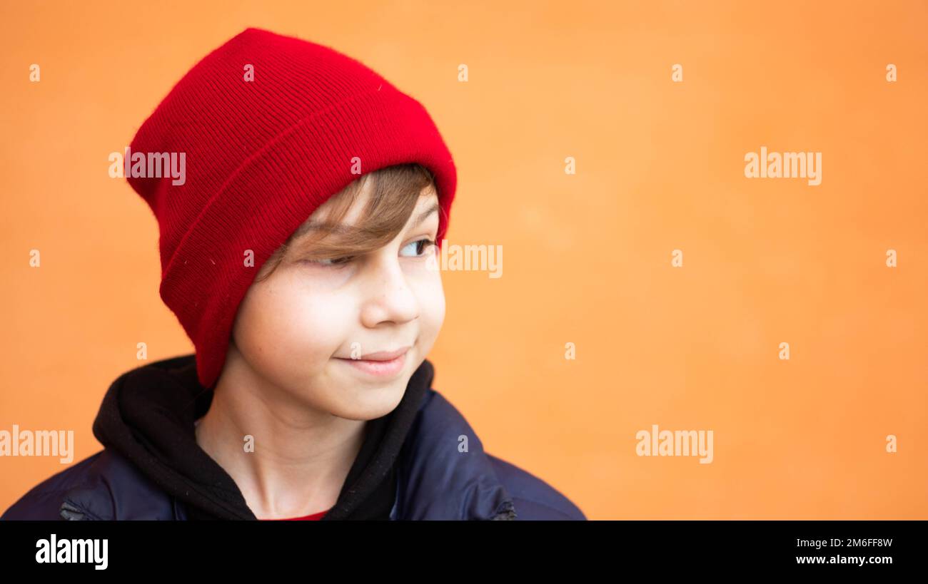 Blond boy red snow hat portrait with orange background Stock Photo