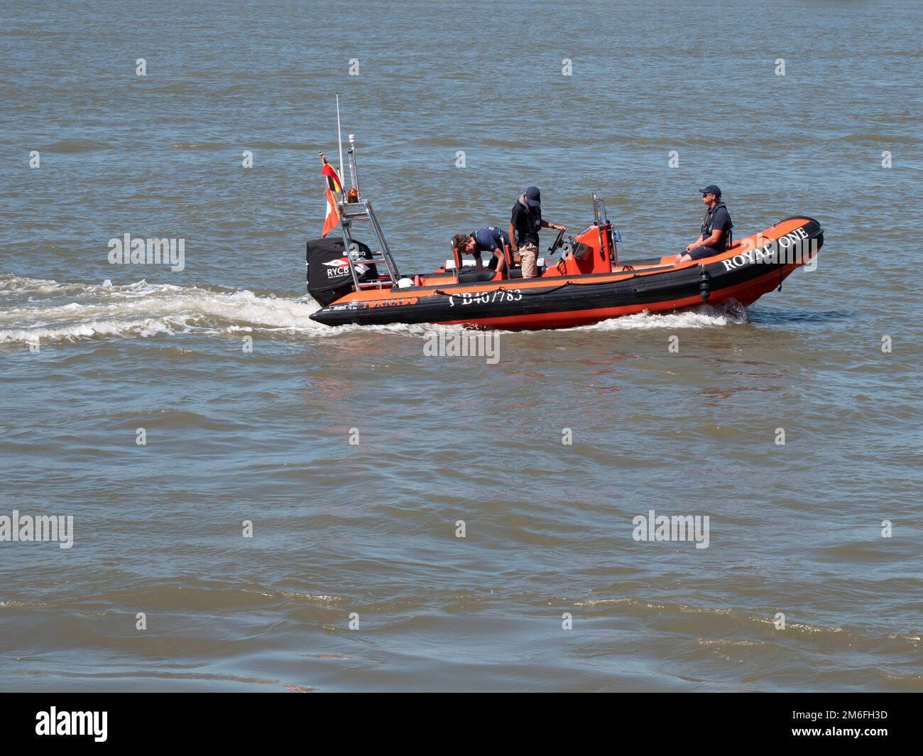 Antwerp, Belgium, July 24, 2022, Orange rubber boat with three persons on board sails near Antwerp on the river Scheldt Stock Photo