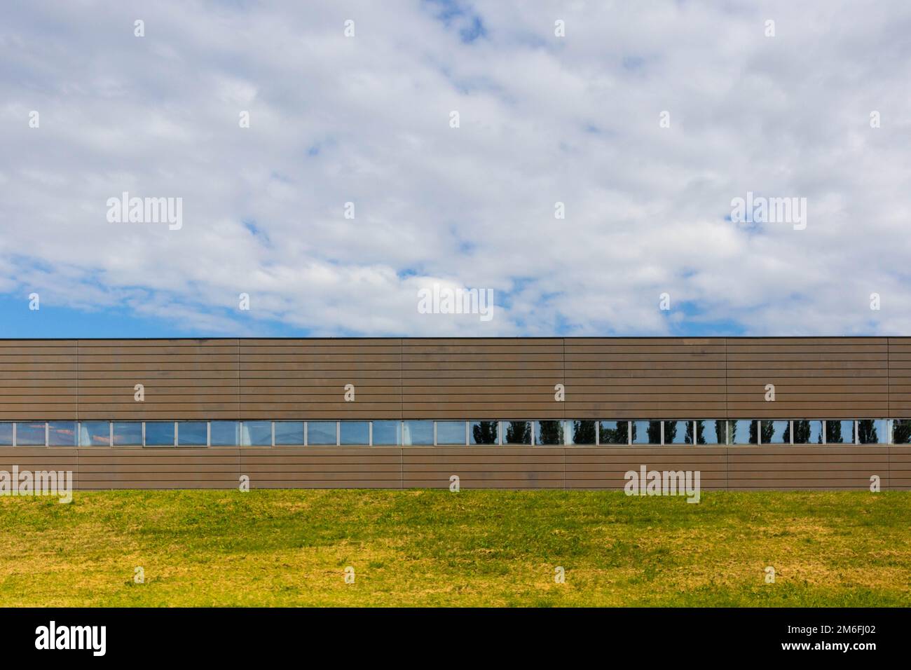 Industrial warehouse office facade view with garden and cloudy sky
