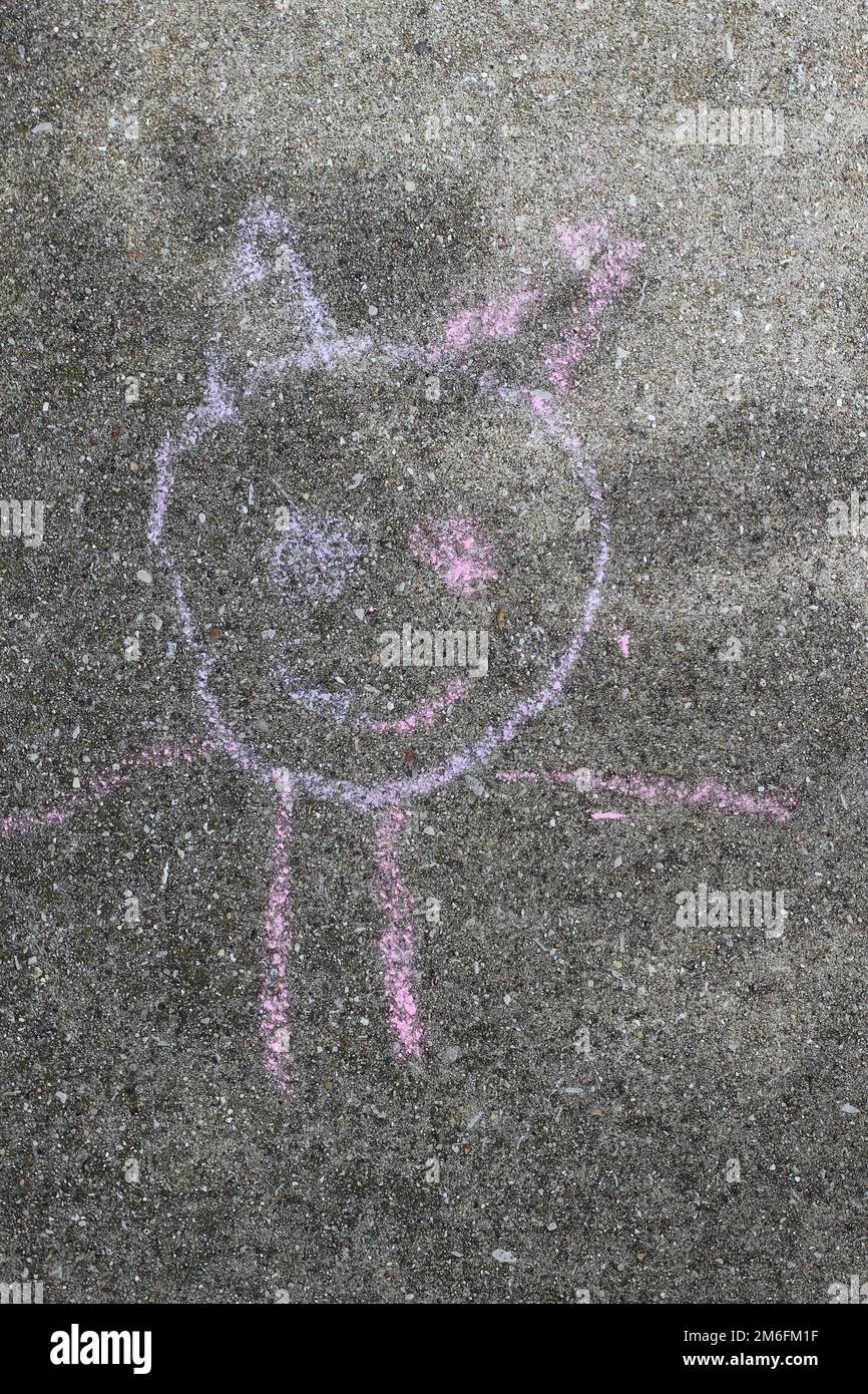 A child's chalk drawings of a smiling happy face on the concrete