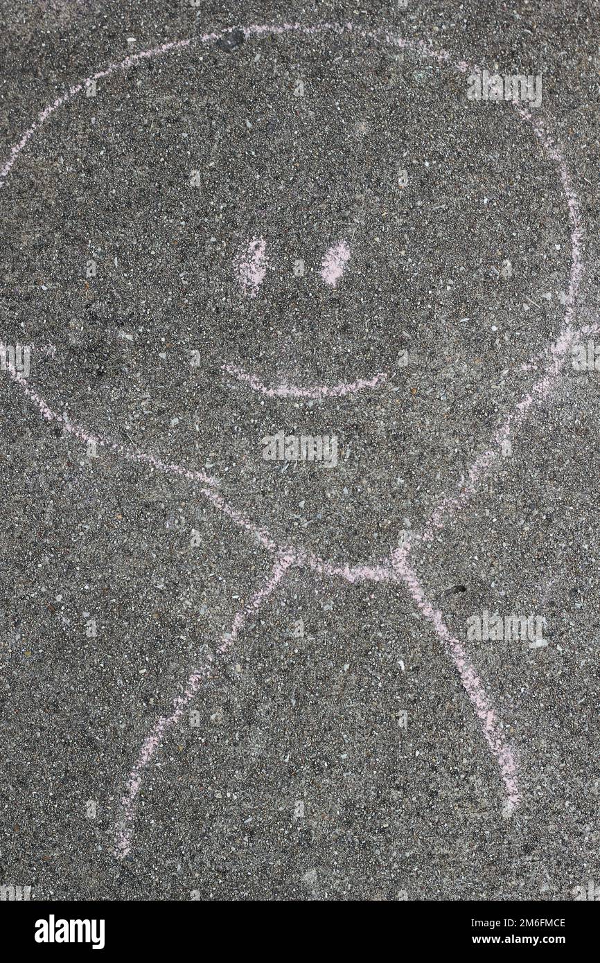 A child's chalk drawings of a smiling happy face on the concrete