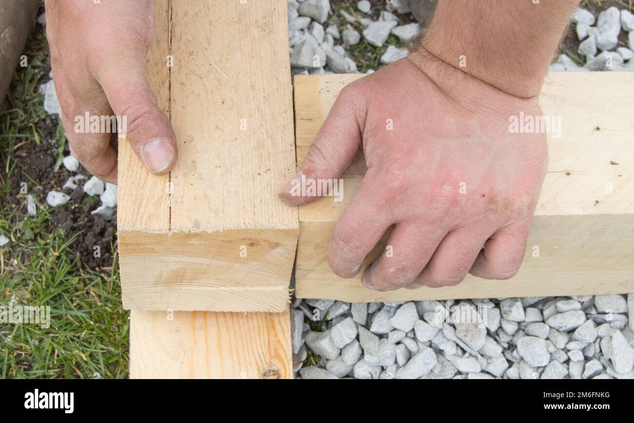 Close-up of rough male hands using new lumber for work, outdoors Stock Photo