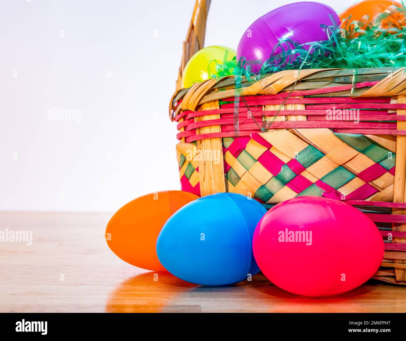 Wicker Easter basket with vintage colorful plastic Easter eggs. Stock Photo