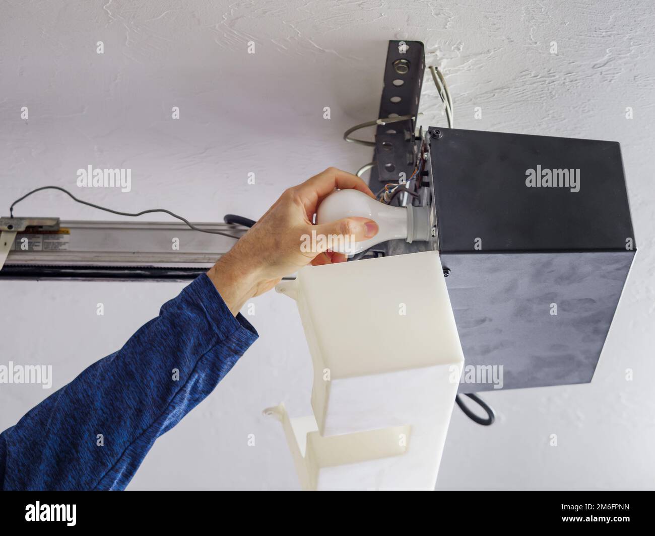 Man replacing light bulb in residential home overhead garage door opener Stock Photo Alamy