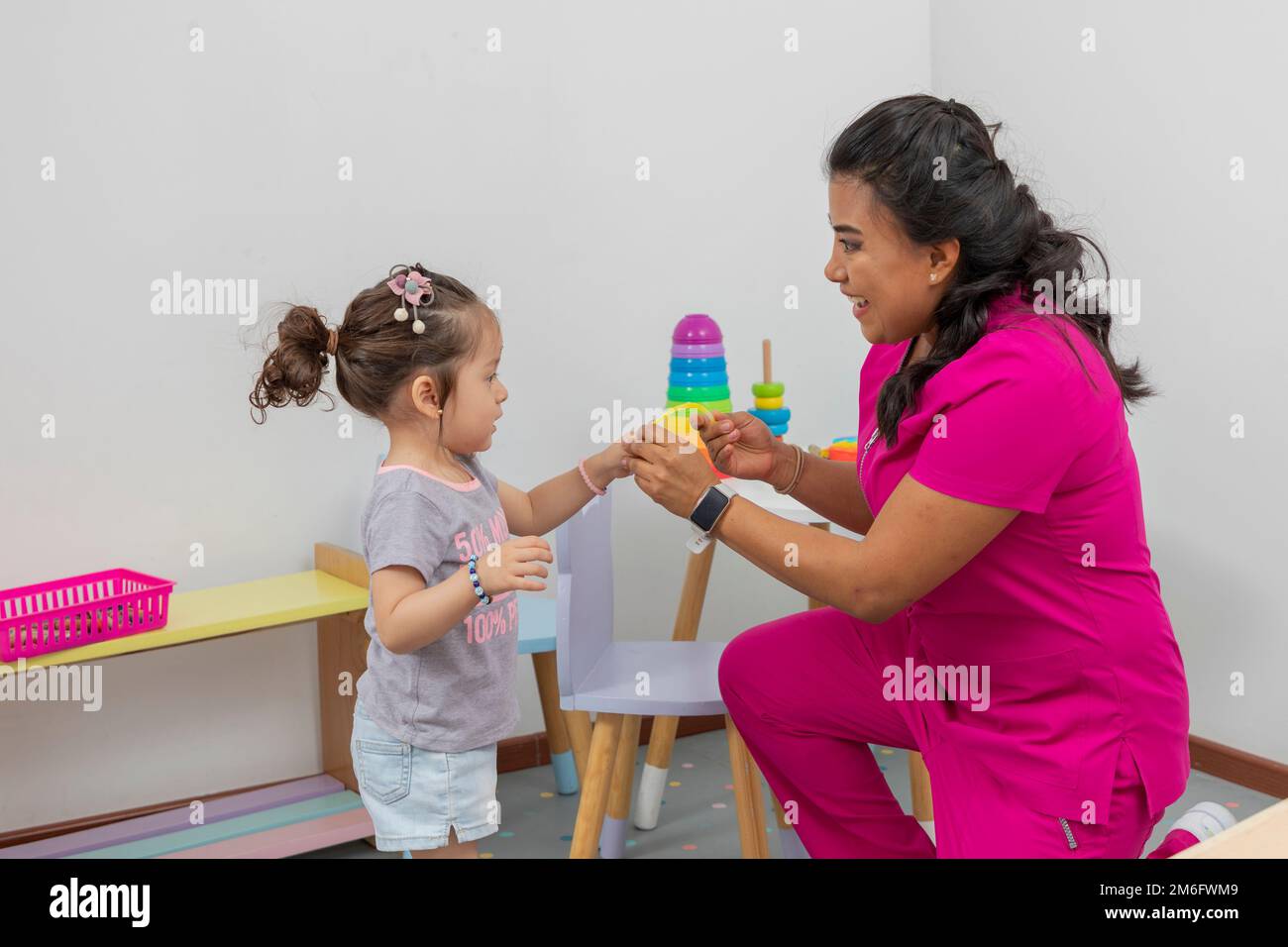 Pediatric doctor places a bracelet on a girl, as a reward after the consultation she gave her. Stock Photo