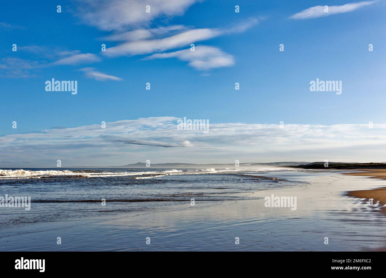 Lossiemouth East Beach Moray coast Scotland a blue sky white clouds and surf from a breaking waves in winter Stock Photo