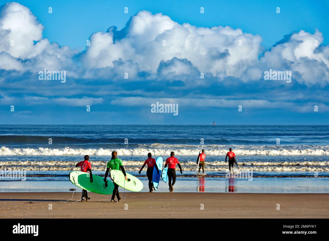 Lossiemouth East Beach Moray coast Scotland six surfers from the New Wave Surf School heading into the sea Stock Photo