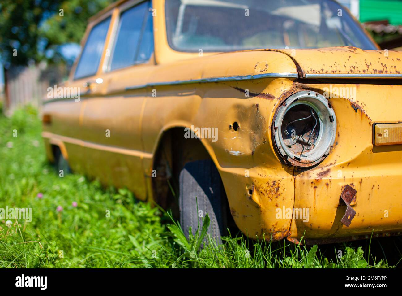 Old yellow wrecked car in vintage style. Abandoned rusty yellow car. Stock Photo