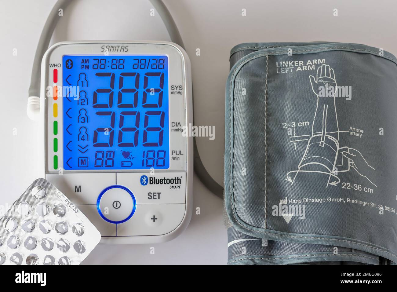 A Sanitas brand digital arm blood pressure monitor and blood pressure pills  on a white surface Stock Photo - Alamy