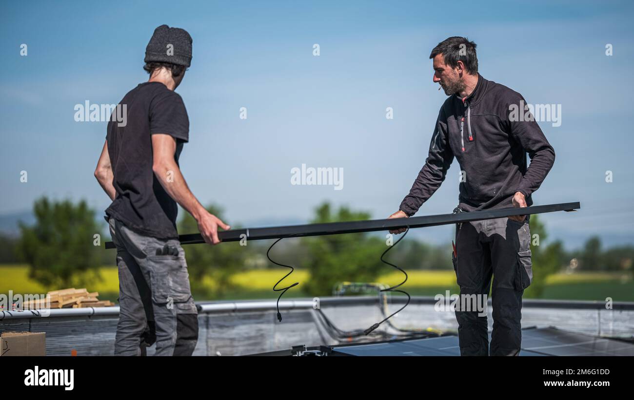 Male team engineers installing stand-alone solar photovoltaic panel ...
