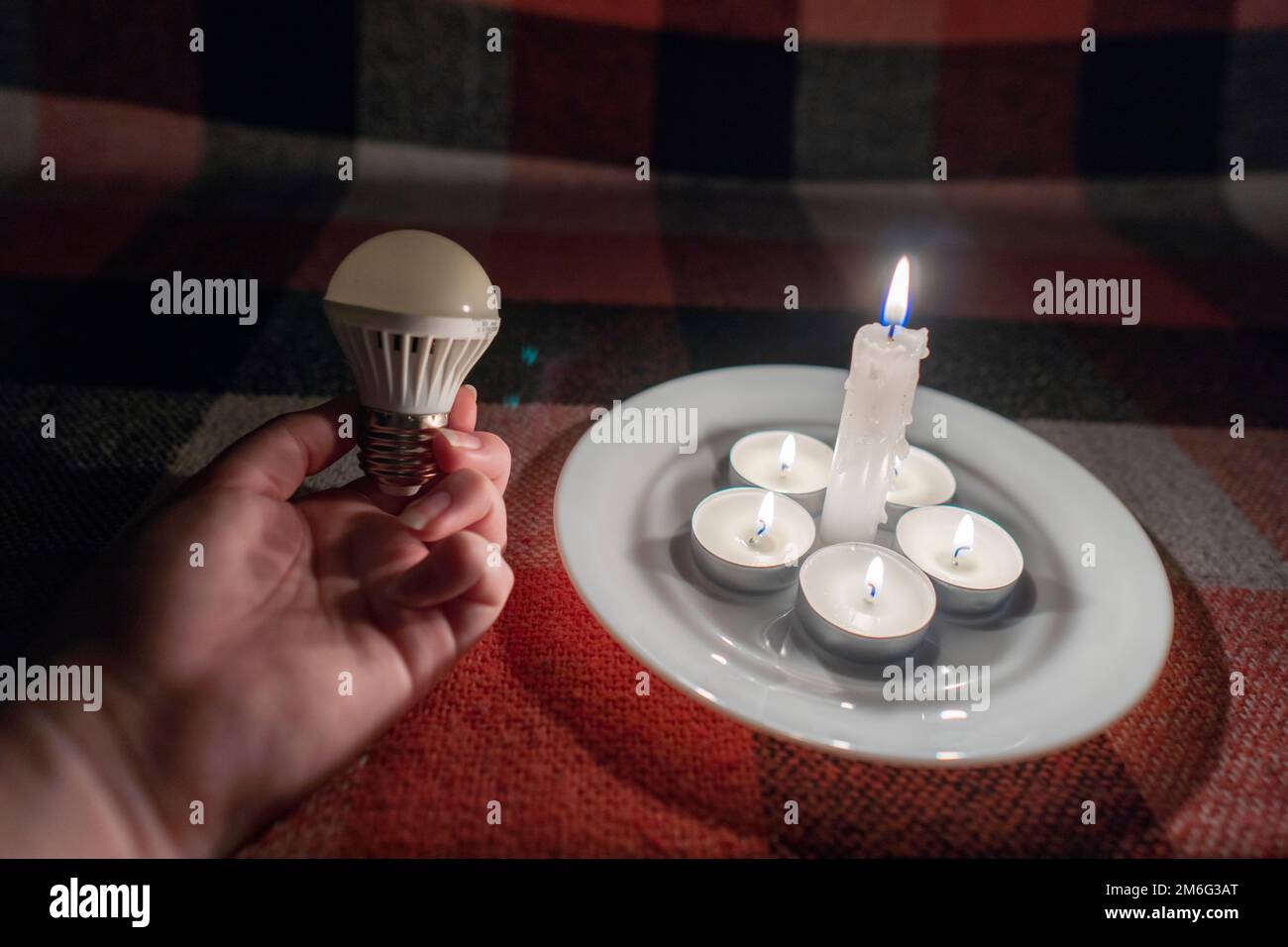 https://c8.alamy.com/comp/2M6G3AT/led-light-bulb-in-hand-against-the-background-of-burning-candles-close-up-power-outage-concept-blackout-energy-crisis-2M6G3AT.jpg