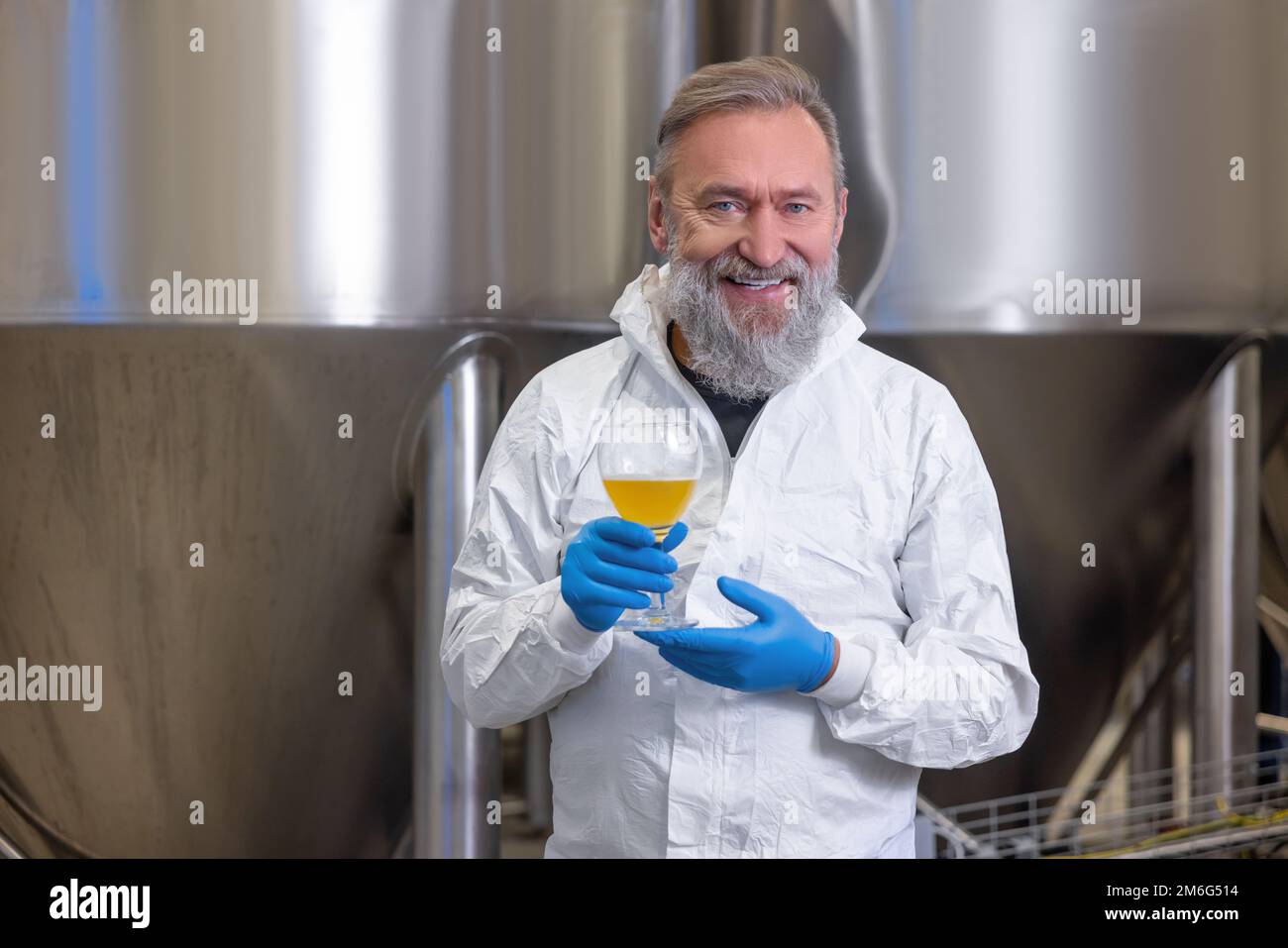 Joyful brewery technologist with a sample of a beverage Stock Photo Alamy
