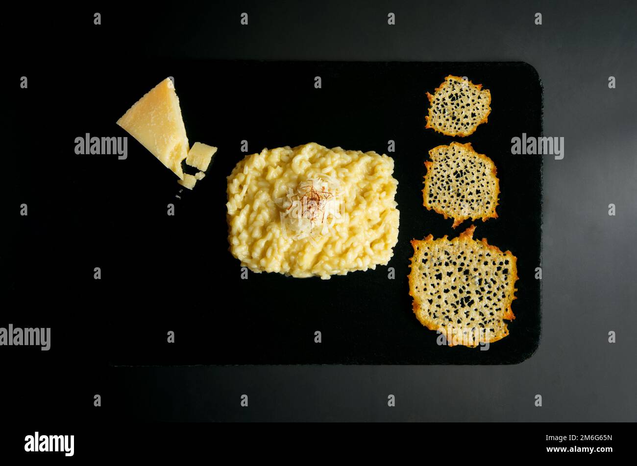 Risotto with safron and parmesan cheese. Risotto is a northern Italian rice dish cooked with broth until it reaches a creamy consistency. Stock Photo