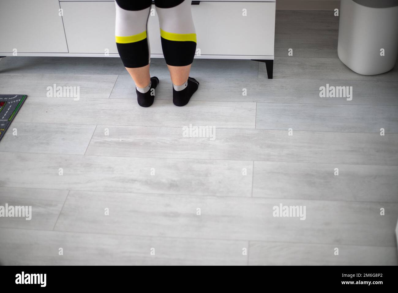 Women's legs with yellow and white black leggings and socks stands in front of a closet. High quality photo Stock Photo