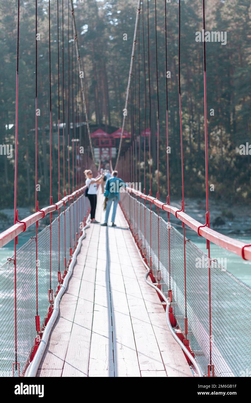A suspension bridge over a wide river in the mountains Stock Photo - Alamy