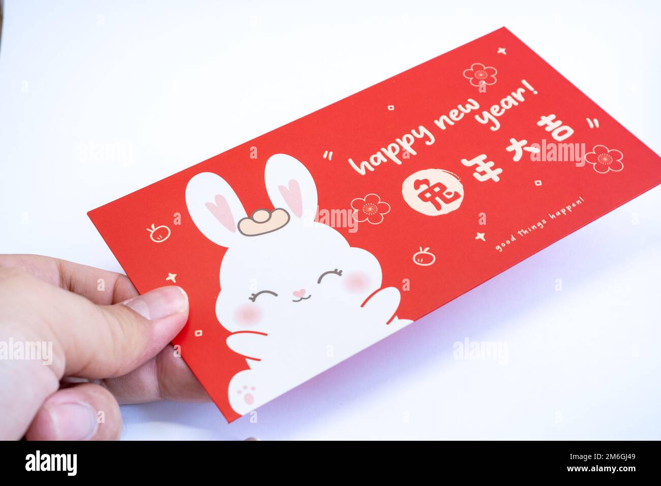 Hand out a Chinese red envelope. Chinese new year concept background . Translation on red envelope: 'Happy New Year of Rabbit' Stock Photo