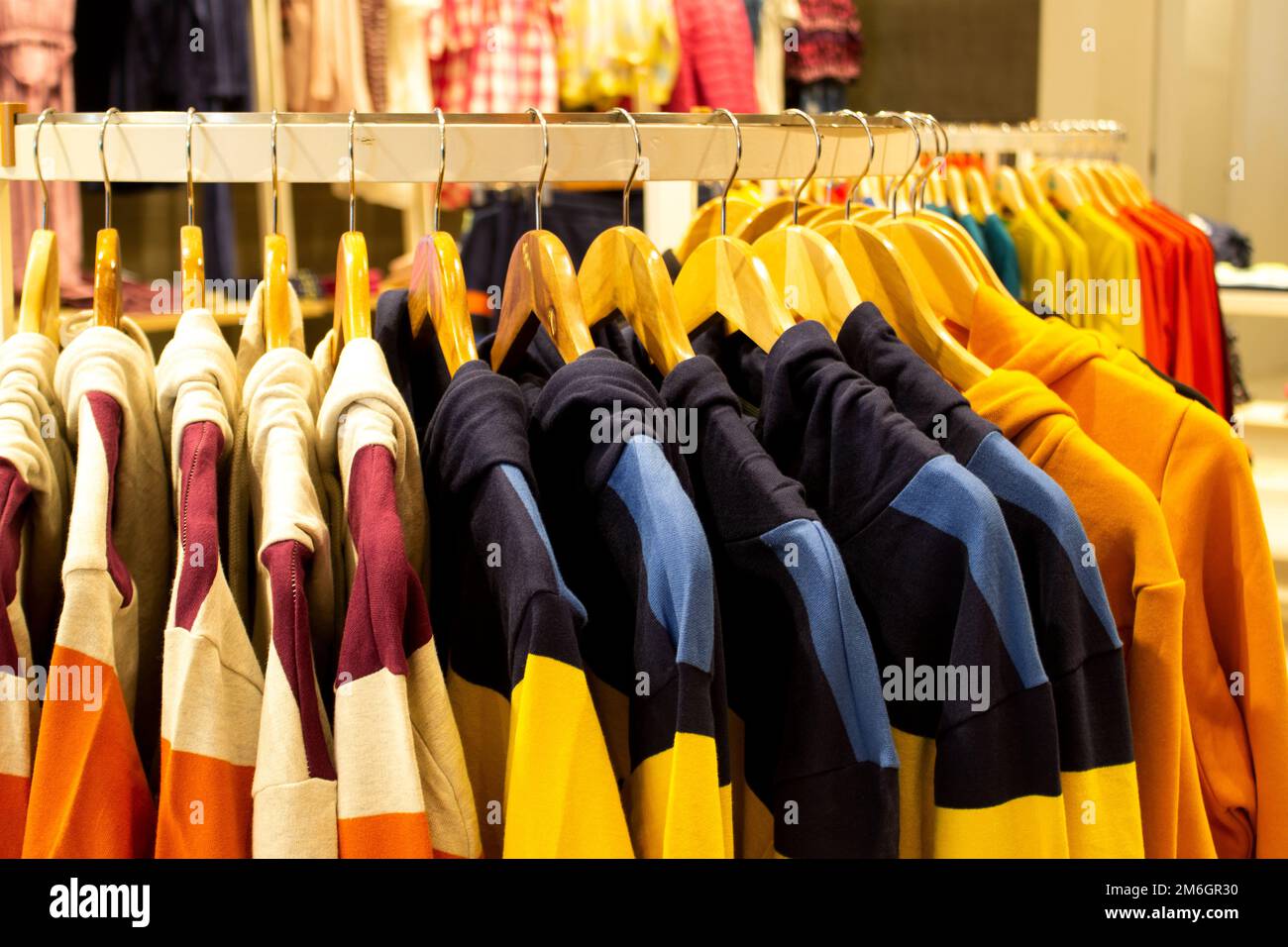 Shirt and pant hanging on hangers on a clothing rack and arranged in shelf in a modern clothe store Stock Photo