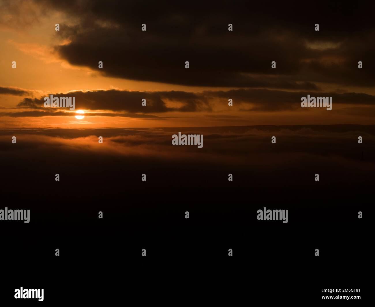An Orange Sun Rise bursts Through Clouds Stock Photo