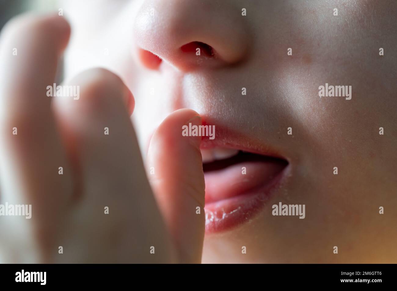 selective focus on a Caucasian child picking their nose and eating the