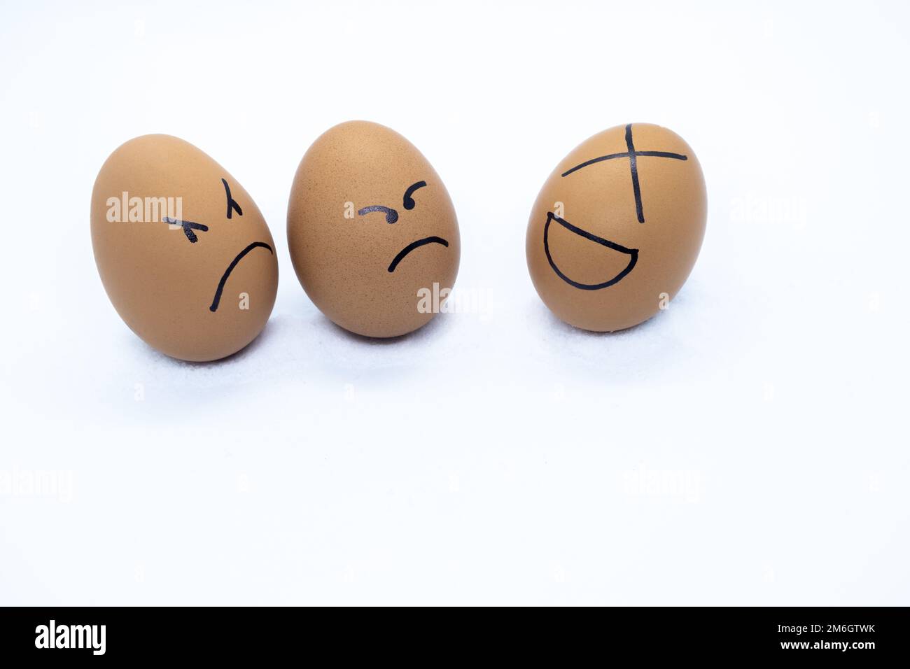 Two angry eggs watching an egg laughing Stock Photo