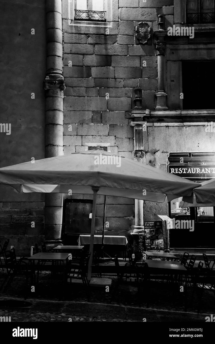 A Black and white view of a street terraza outside a restaurant with empty tables early in the evening in Segovia Spain. Stock Photo