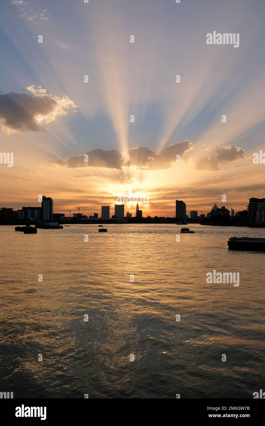 Golden rays of sun shine out from behind the Shard in the distance over the river thames at sunset in London Stock Photo