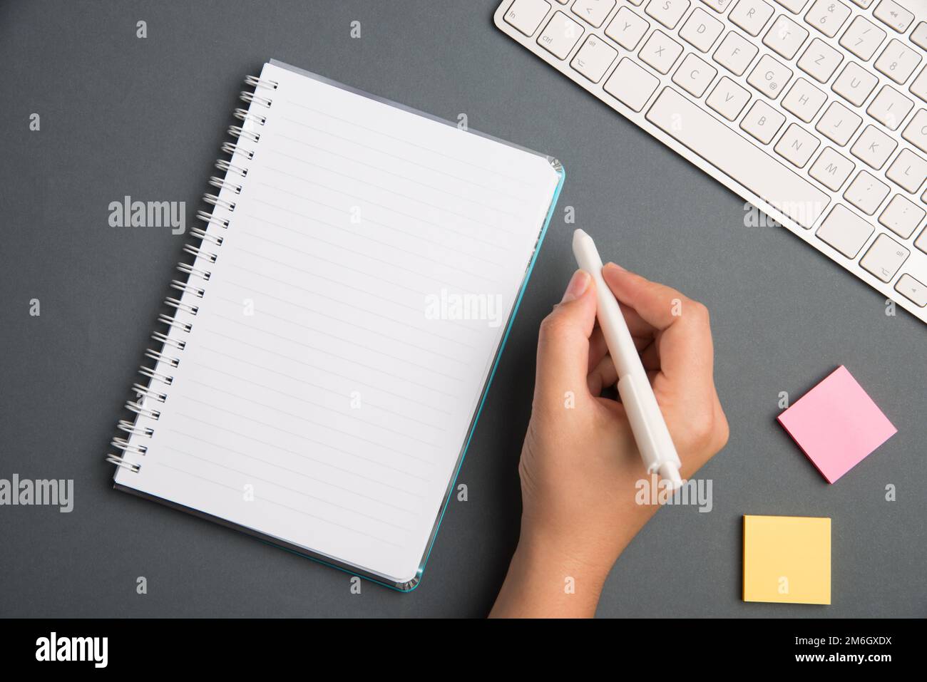 Keyboard Over A Table Beside A Notebook And Pens With Sticky Notes. Computer Keypad On Top Of A Desk With A Office Supplies And Stock Photo