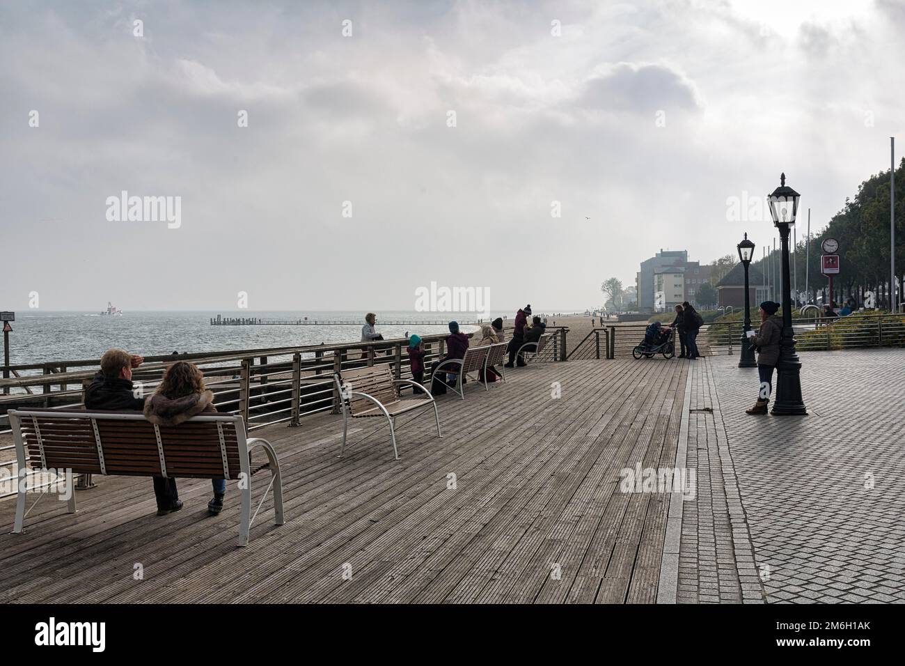 Pedestrians sitting on benches, looking at the sea, dreary autumn weather, haze, Wyk auf Foehr promenade, Foehr Island, North Frisia, North Sea Stock Photo
