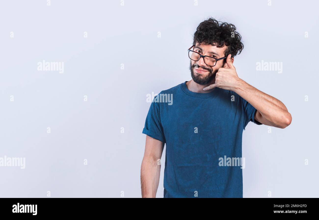 Person making call gesture with fingers. Handsome man imitating a phone conversation, Young man making call gesture on isolated background Stock Photo
