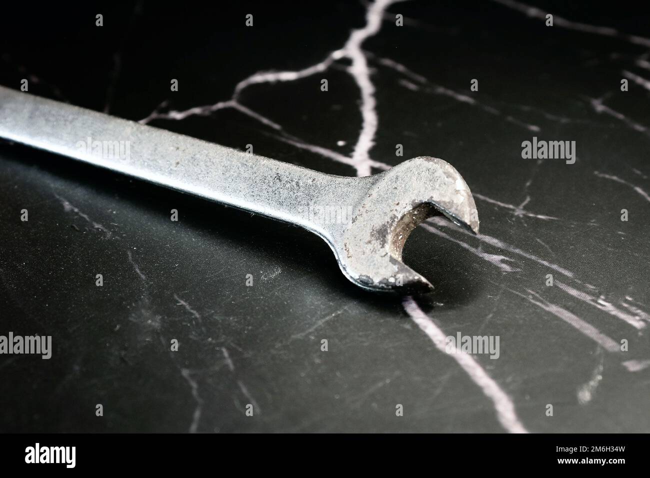 old rusty fixed wrench for nuts on a dark marble background Stock Photo